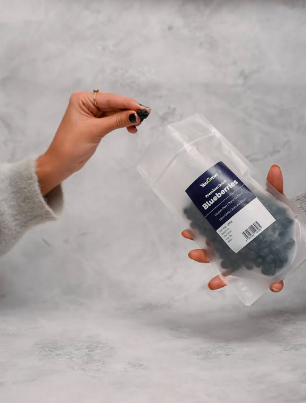 Person holding a container of blueberries against a gray background